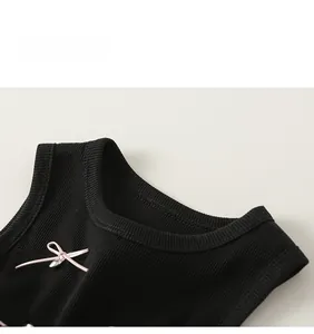 Detail of black ribbed cotton sleeveless dress with a pink ribbon bow and bead accent