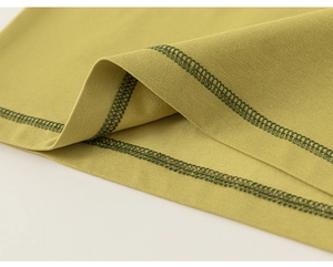 Dettaglio di una t-shirt per bambini verde senape con cuciture piatte e tessuto a maglia fine