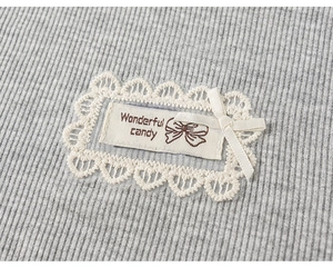 Detailed macro view of gray knitted fabric with lace tag and white silk bow accent