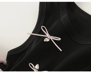 Detail of pink bow and silver heart pendant on black ribbed knit girl's dress
