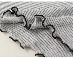 Close-up of gray ribbed knit fabric with black lettuce edge trim on girl's clothing set
