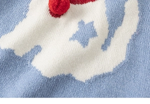 Detalle del chaleco de punto azul con motivos de estrellas, nubes y pompón rojo