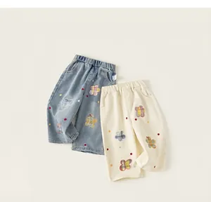 Detalle de pantalones vaqueros infantiles con bordados de flores a cuadros arcoíris