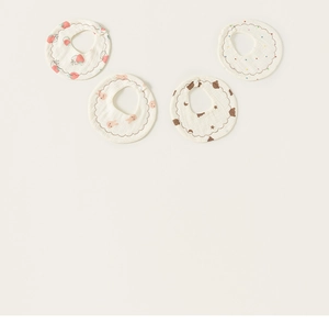 Detail view of four cotton petal-shaped baby bibs with strawberry and rabbit patterns