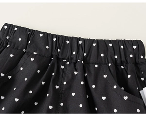 Detail of girls black polka dot shorts featuring elastic waistband and pocket stitching