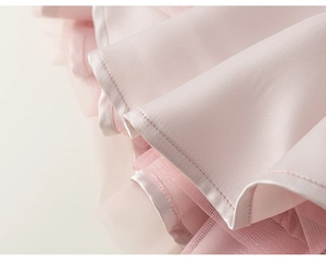 Detail of light pink layered mesh and satin fabric hemline on a girl's party dress