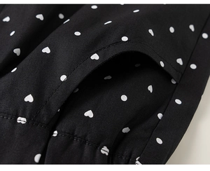 Detailed macro view of girls' black fabric with white heart and polka dot prints