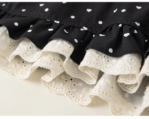 Macro detail of girls' black polka dot fabric featuring double-layer white eyelet lace trim