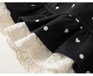 Detailed view of black polka dot fabric with elegant beige lace embroidery and ruffles