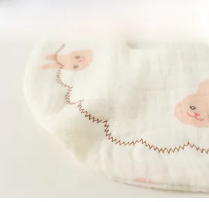 Detail of soft cotton baby bib with rabbit print and brown scalloped edge stitching