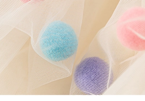 Vue détaillée du tissu en tulle souple orné de pompons en peluche 3D colorés et doux