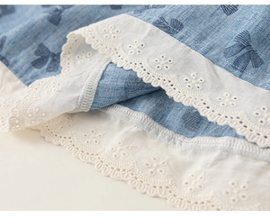 Detailed view of light blue dress hem with floral lace trim and blue bow patterns
