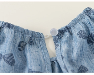 Detailed macro view of light blue cotton fabric with bow prints and neckline button detail
