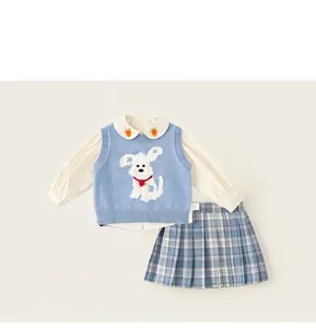 Detalle de camisa blanca bordada con zanahoria y chaleco de punto azul para niñas