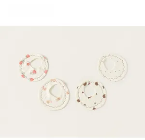 Flat lay of four cotton baby bibs with strawberry, rabbit, bear, and dot patterns