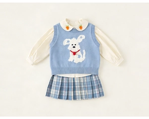 Detalle de chaleco azul con motivo de perrito, camisa blanca y falda plisada a cuadros