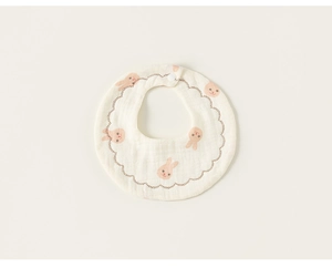 Detail of soft cotton baby bib with pink bunny patterns and brown wavy scalloped edges