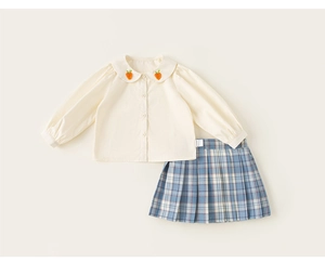 Detalle de ropa escolar para niñas con bordado de zanahoria y falda plisada a cuadros