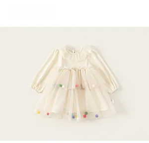 Détail d'une robe en tulle pour enfant avec pompons colorés et col à volants