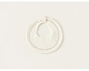 Detail of baby bib showing breathable cotton gauze fabric and brown scalloped edges