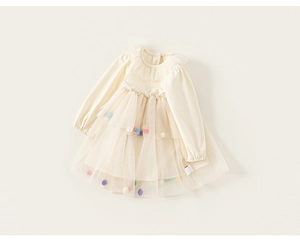 Détail d'une robe en tulle pour bébé avec pompons colorés et encolure à volants doux