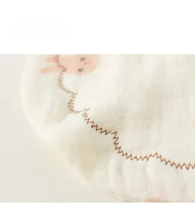 Macro shot of cotton baby bib showing pink rabbit patterns and breathable gauze texture