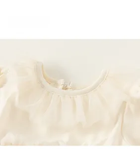Détail du col rond avec dentelle de tulle multicouche sur la robe pour enfant de couleur beige