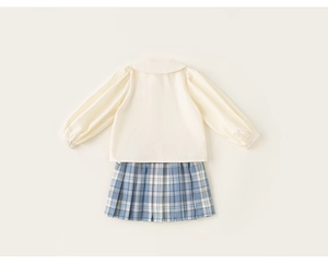 Detalle en plano de conjunto escolar para niña con camisa crema y falda plisada a cuadros