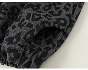 Detail of leopard print kids pants showing knit texture, pocket, and elastic waistband