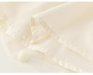 Détail d'une robe pour enfant blanc cassé avec coutures fines et couches de tulle