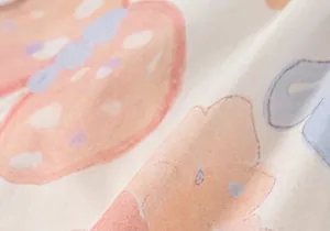 Nahaufnahme aus weichem Baumwollstoff mit bunten Cartoon-Drucken auf cremeweißem Grund