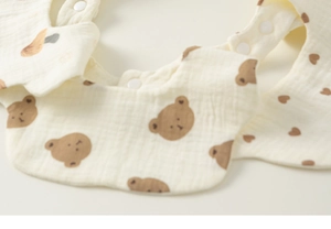 Close-up of baby cotton gauze bib featuring brown bear pattern and snap button closure