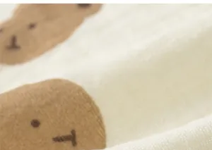 Macro detail of soft cream double-layer cotton gauze fabric with brown cartoon bear print