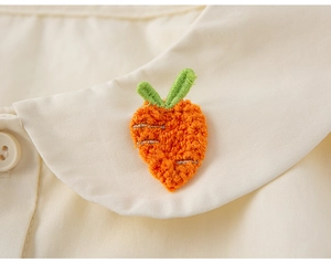 Detalle de un cuello de muñeca con bordado de zanahoria 3D en camisa blanca