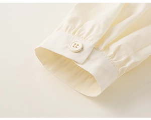 Detalle del puño plisado de camisa con botón para conjunto escolar de niñas