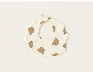 Close-up of petal-shaped cream baby bib featuring brown bear print and soft cotton gauze texture