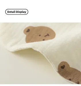 Detail showing soft cotton gauze texture and cute brown bear patterns on baby bib