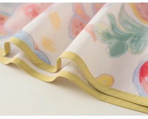 Nahaufnahme von leichtem Baumwollstoff mit bunten Fruchtprints und gelben Paspelkanten