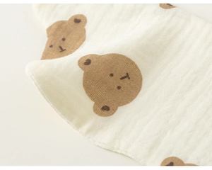 Close-up of soft cotton gauze baby bib with cute brown bear patterns and textured fabric