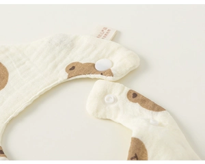 Close-up of baby bib featuring cartoon bear pattern and snap button closure