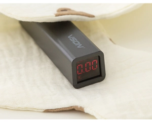 Macro shot of VSON handheld fluorescence detector showing 0.00 reading on a cotton fabric