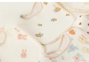 Close-up of soft cotton gauze baby bibs with cartoon rabbit and fruit prints