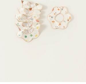 Detail view of floral cotton baby bibs with mushroom patterns and snap buttons