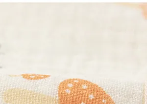 Close-up detail of soft cotton gauze fabric with cute orange mushroom print