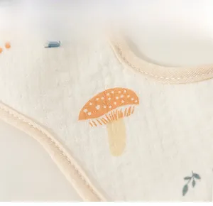 Gros plan d'un bavoir en coton pour bébé avec motif de champignons et texture douce
