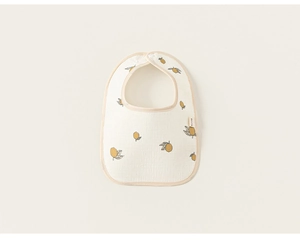 Detailed close-up of a soft cotton baby bib featuring a yellow lemon print and snap button