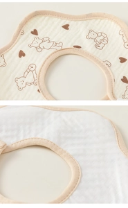 Close-up of petal-shaped baby bib showing soft gauze texture and cute bear print