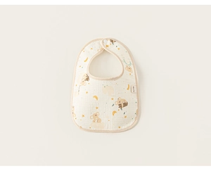 Detail of soft cotton baby bib with koala print and snap closure on beige background