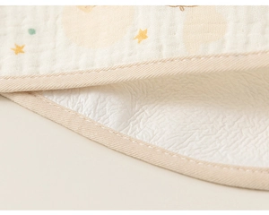 Close-up of baby cotton gauze bib featuring yellow star patterns and waffle texture