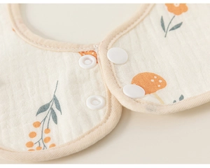 Detail of baby bib showing breathable cotton gauze fabric and adjustable resin buttons